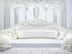 a white couch sitting in front of a window covered in flowers