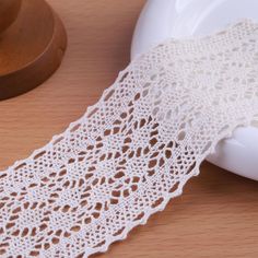 a piece of white crocheted lace next to a wooden bowl