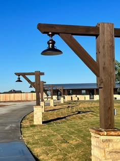 a bell on top of a wooden structure in the middle of a grassy area next to a road