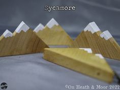 three wooden mountains sitting on top of a gray surface with the words syoamore written above them