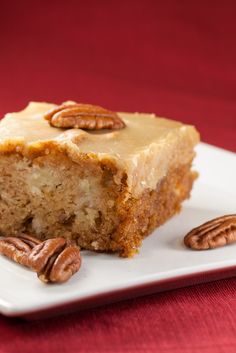 a piece of cake sitting on top of a white plate with pecans around it