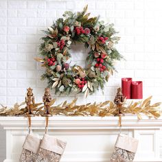 christmas stockings hanging on a mantel decorated with holly wreaths and gold leafy garland