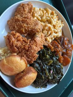 a white plate topped with fried chicken, macaroni and cheese and other foods