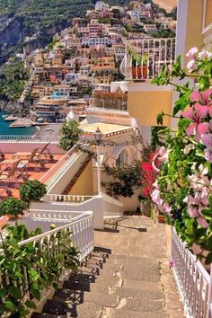 stairs leading up to the beach with flowers growing on them and buildings in the background