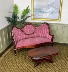 a living room with a pink couch and coffee table in front of a painting on the wall