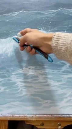 a person holding a pair of scissors in front of a table with water on it