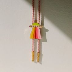 two necklaces with different colored beads hanging from the side on a white wall next to each other