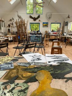 an artist's studio with several paintings and chairs in it, all on the floor