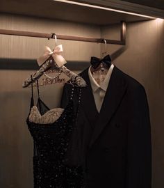 two clothes hang on a coat rack in a dressing room, one is black and the other is white