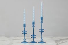 three blue candles sitting on top of a marble table