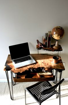 a laptop computer sitting on top of a wooden desk next to a chair and table