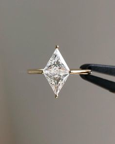 a close up of a diamond being held by a pair of tongs in front of a gray background