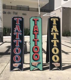 three signs that say tattoo on them in front of a building