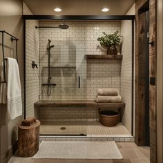 a walk in shower sitting next to a wooden bench and towel rack on top of a tiled floor