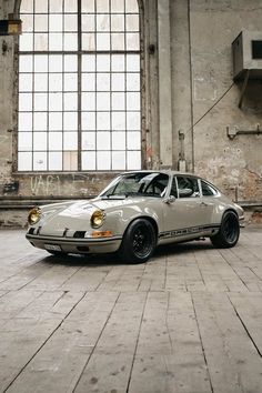 an old white car parked in front of a large window