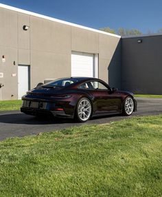 a maroon sports car parked in front of a building