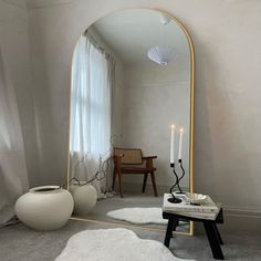 a mirror sitting on top of a floor next to a table with a candle in it