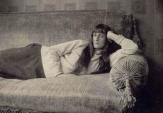 black and white photograph of a woman laying on a couch with her hands behind her head