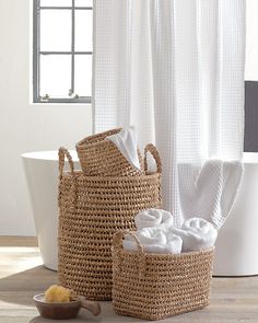 two wicker baskets sitting next to each other in front of a bathtub and shower curtain