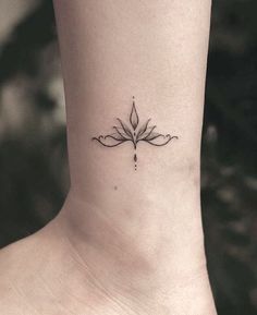 a black and white photo of a small tattoo on the ankle that has a flower in it