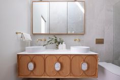 a bathroom with two sinks and a large mirror above the sink, along with a toilet