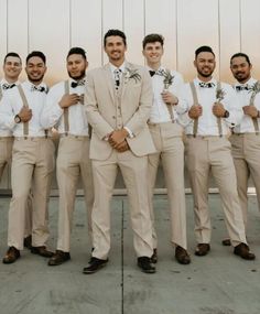 a group of men standing next to each other wearing tan suits and bow ties with flowers in their lapels