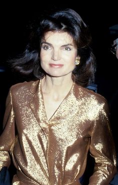 a woman in a shiny gold dress posing for the camera with her hands on her hips