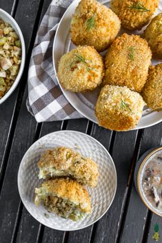 several plates with food on them sitting on a wooden table next to bowls and spoons