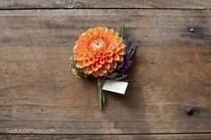 an orange flower is placed on a wooden surface with a price tag attached to it