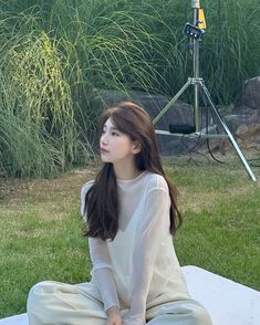 a young woman sitting on the ground in front of a camera set up for a photo