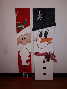 two snowmen painted on wooden boards in the shape of santa claus and mrs claus