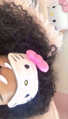 a woman with curly hair wearing a hello kitty mask