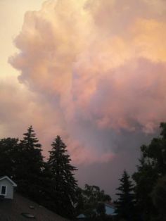 the sky is filled with pink clouds and green trees