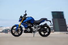 a blue and black motorcycle parked in front of a tall building with a sky background