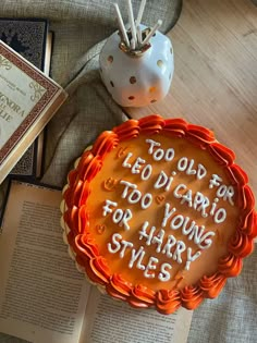 there is a cake with writing on it next to an open book and a candle