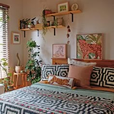 a bed sitting in a bedroom next to a window with plants on top of it