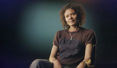 a woman sitting on top of a chair in front of a dark background with lights