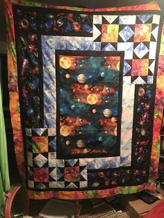 a quilted wall hanging in the corner of a room