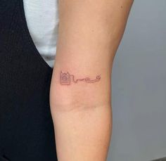 a woman's arm with a small camera tattoo on the left side of her arm