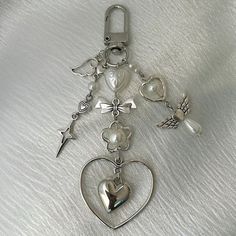 a heart shaped keychain with charms attached to it on a white cloth background