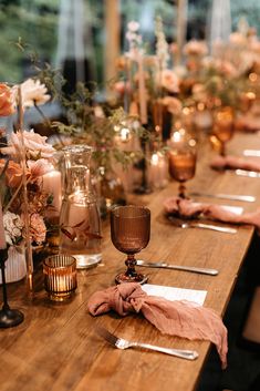 a long table with candles, flowers and napkins sitting on it's side