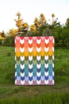 a multicolored chevron quilt sitting in the grass