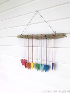 a group of hearts hanging from a wooden beam on a wall with string attached to it