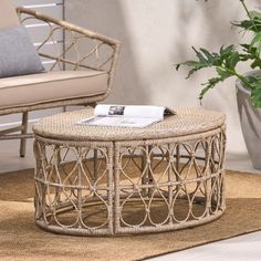 a wicker coffee table sitting on top of a rug next to a chair and potted plant