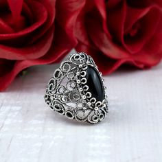 This stunning cocktail ring features an intricate filigree lace design and a 7x14 mm black onyx gemstone. Black onyx is a stone of protection and grounding, making it the perfect choice for a statement cocktail ring. It is said to absorb negative energy and promote inner strength.  Ring Face Length is 0.65 inches and Width is 0.30 inches  The ring is made from high-quality 925 sterling silver and is finished to a high shine. The lace detailing is exquisitely crafted and adds a touch of elegance to the ring. The ring comes with a silver polish cloth and a luxurious gift box, making it the perfect gift for any special occasion. This statement piece is perfect for any occasion, from a night out on the town to a special event. It is sure to turn heads wherever you go. Whether you are looking f Ornate Black Sterling Silver Rings, Black Filigree Ring, Ornate Black Wedding Ring, Ornate Black Filigree Jewelry, Ornate Black Jewelry With Intricate Design, Black Ring With Intricate Design, Black Filigree Ring Jewelry, Black Victorian Filigree Rings, Ornate Black Oval Ring