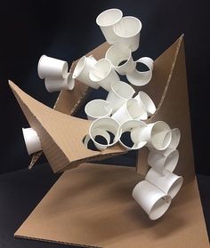 a sculpture made out of white cups sitting on top of a brown cardboard box,