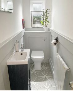 a white toilet sitting next to a sink in a bathroom under a window near a radiator