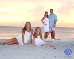 a family poses on the beach at sunset