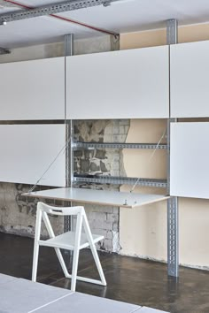 a white chair sitting next to a table in a room filled with shelves and shelving