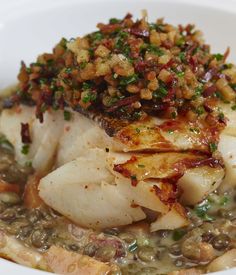 a white bowl filled with fish covered in sauce